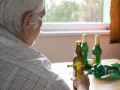 Starszy mężczyzna z butelkami piwa. Alkoholizm po 70. to trudna walka.