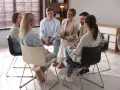 Grupa ludzi siedzi w kręgu, słuchając terapeuty. To scena z ośrodka dla uzależnionych, gdzie wsparcie i zrozumienie pomagają w powrocie do zdrowia.