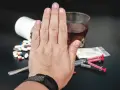 Dłoń zatrzymuje rozrzucone tabletki, strzykawki, biały proszek i alkohol. To symbol walki z uzależnieniem mieszanym.