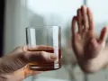 Dłoń odrzuca szklankę z alkoholem, symbolizując koniec z nałogiem i wyciek z wszywki.