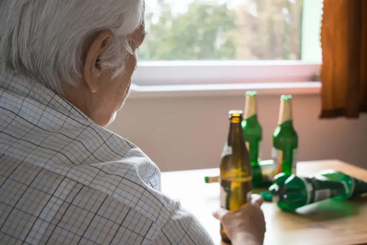 Starszy mężczyzna z butelkami piwa. Alkoholizm po 70. to trudna walka.