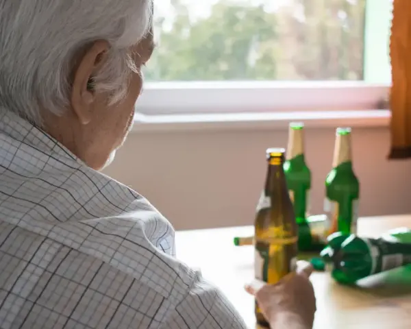 Starszy mężczyzna z butelkami piwa. Alkoholizm po 70. to trudna walka.
