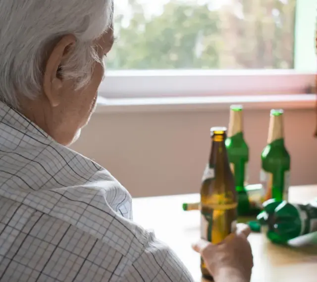 Starszy mężczyzna z butelkami piwa. Alkoholizm po 70. to trudna walka.